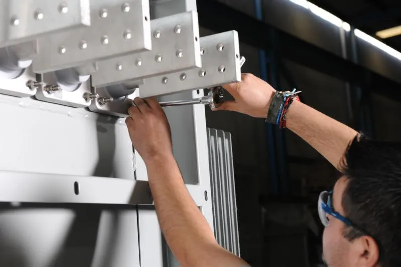 Technician assembling metal bracket component with wrench during transformer manufacturing